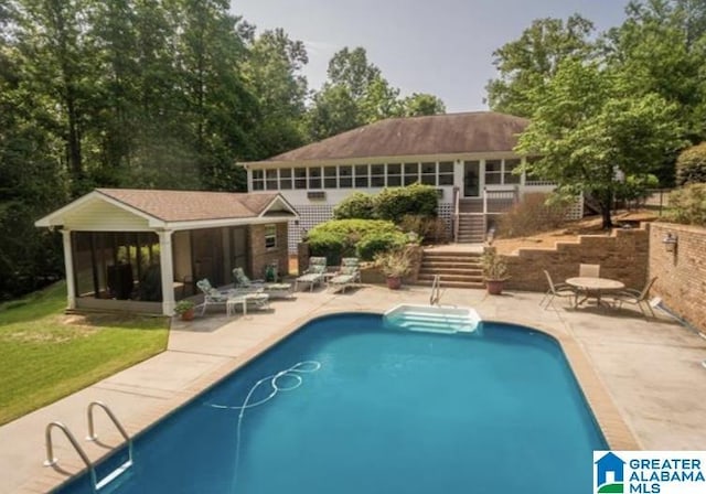 view of swimming pool with a sunroom, an outdoor structure, and a patio