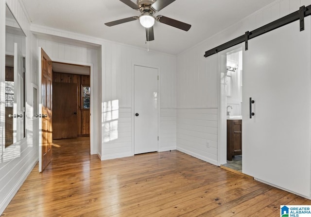 empty room featuring crown molding, light hardwood / wood-style floors, and a barn door