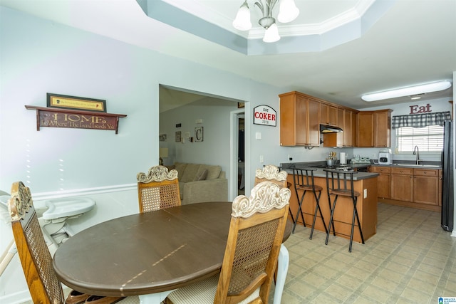 dining space featuring ornamental molding, sink, a chandelier, and a tray ceiling