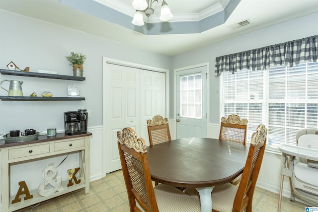 dining area with an inviting chandelier, ornamental molding, and a raised ceiling