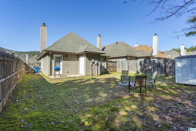 rear view of property featuring a lawn, a storage unit, and an outdoor fire pit