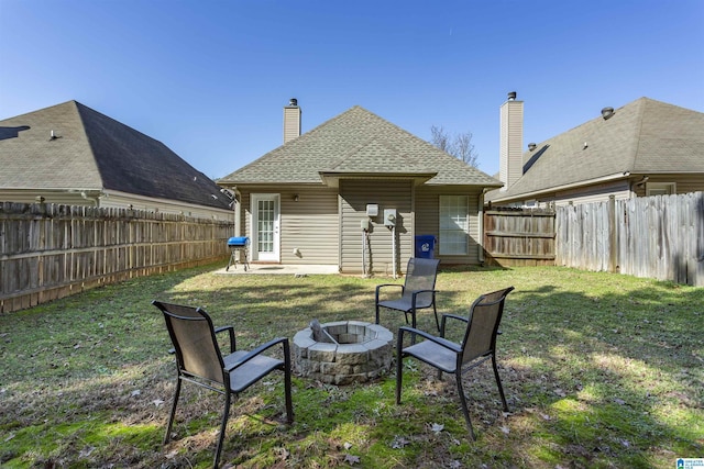 back of property featuring a yard, a patio area, and an outdoor fire pit