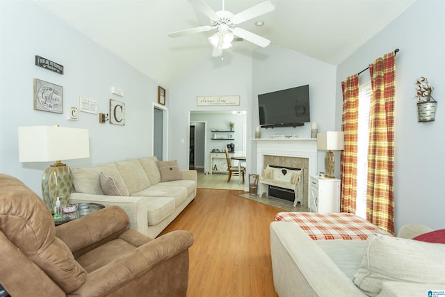 living room with ceiling fan, a fireplace, high vaulted ceiling, and light hardwood / wood-style flooring