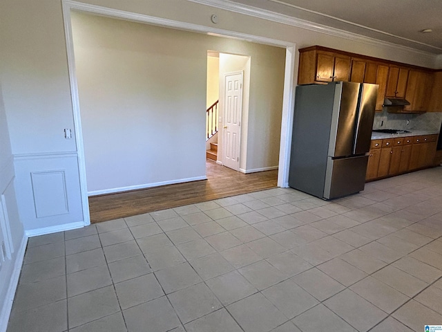 kitchen with crown molding, light tile patterned floors, and stainless steel fridge