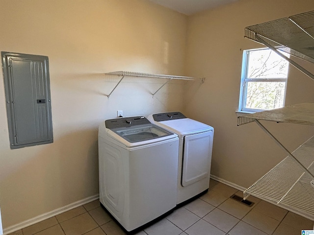 washroom with light tile patterned floors, electric panel, and washing machine and dryer