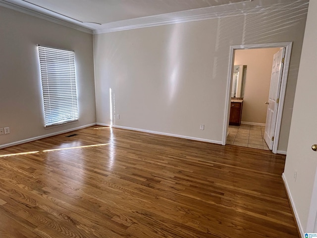 empty room with crown molding and wood-type flooring