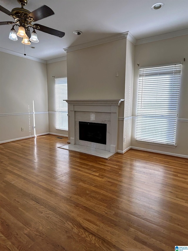 unfurnished living room with hardwood / wood-style flooring, crown molding, ceiling fan, and a fireplace