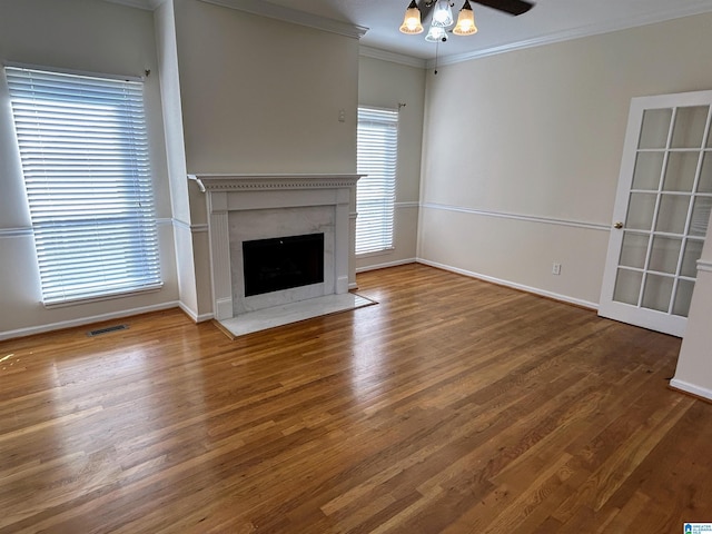 unfurnished living room featuring ornamental molding, wood-type flooring, ceiling fan, and a fireplace