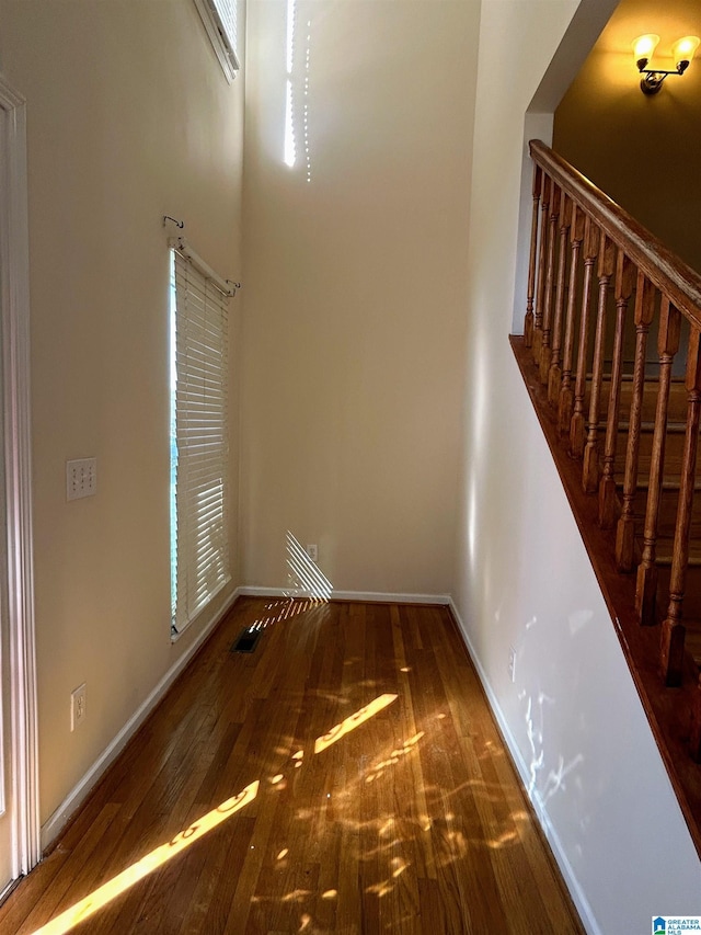 interior space featuring a towering ceiling and wood-type flooring