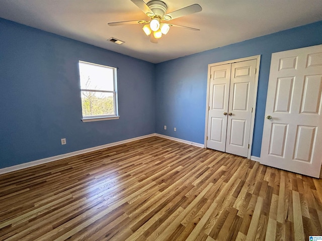 unfurnished bedroom featuring wood-type flooring, ceiling fan, and a closet