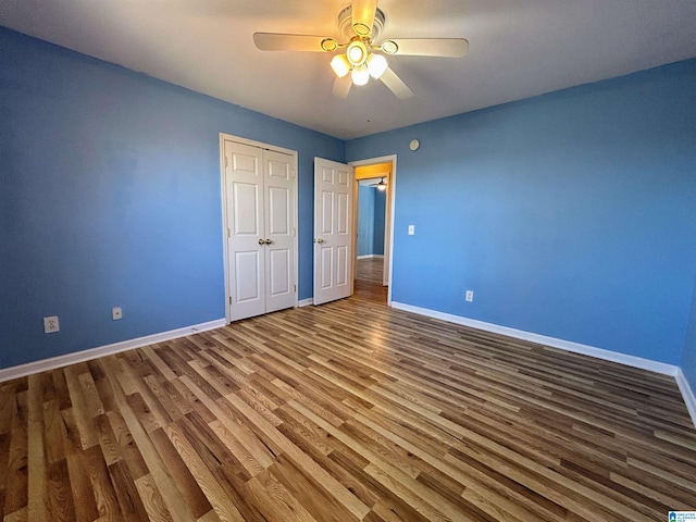 unfurnished bedroom featuring dark wood-type flooring, ceiling fan, and a closet