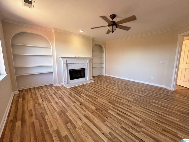 unfurnished living room featuring hardwood / wood-style flooring, crown molding, and built in features