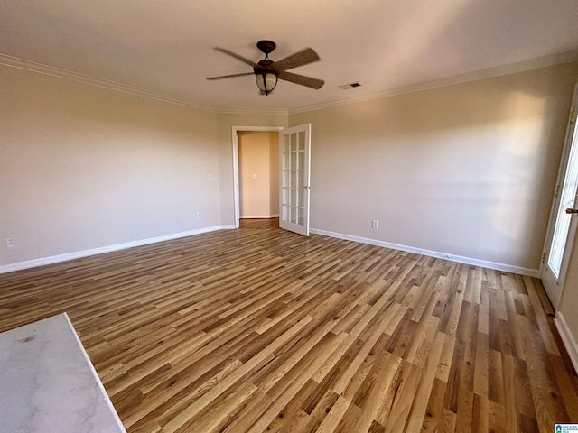 empty room with crown molding, french doors, ceiling fan, and hardwood / wood-style flooring