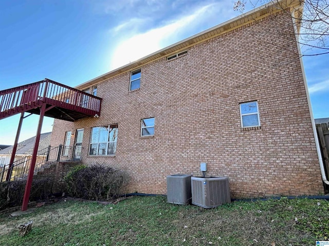 view of property exterior with cooling unit, a yard, and a deck