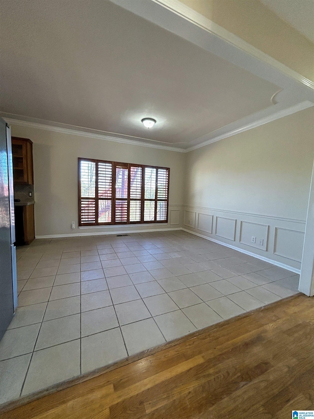 unfurnished living room with light tile patterned flooring and ornamental molding