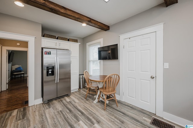 kitchen featuring white cabinetry, beam ceiling, light hardwood / wood-style flooring, and stainless steel refrigerator with ice dispenser