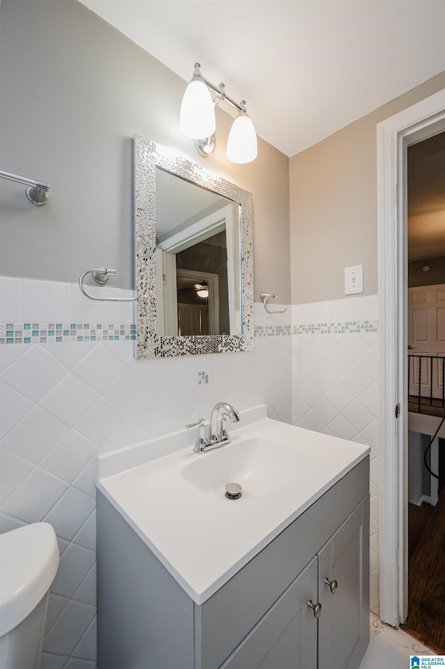 bathroom featuring vanity, tile walls, and toilet