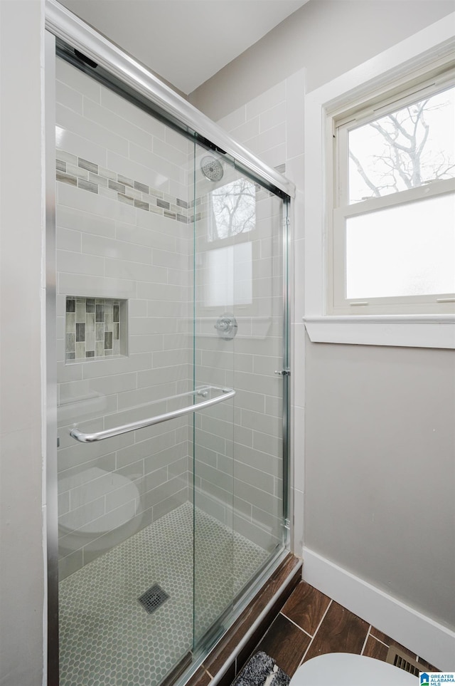 bathroom featuring a shower with door, wood-type flooring, and toilet