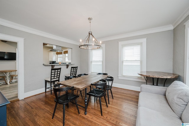 dining space with crown molding, wood-type flooring, and a chandelier