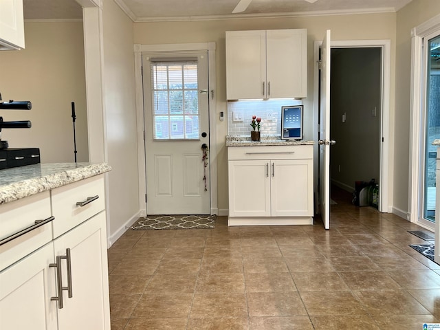 kitchen with white cabinetry, light stone counters, ornamental molding, and decorative backsplash