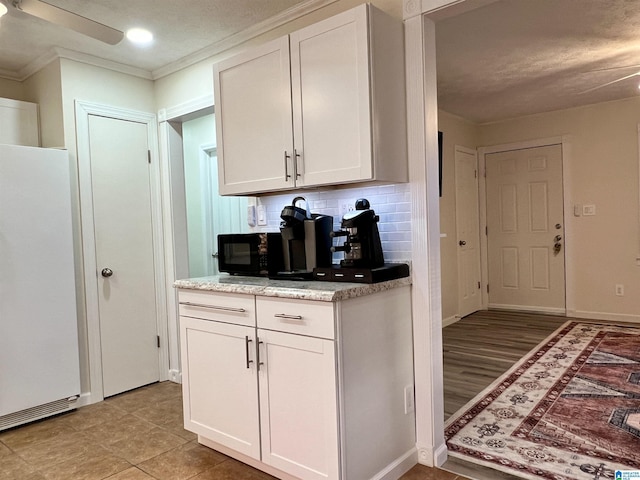 kitchen featuring white cabinetry, tasteful backsplash, crown molding, white fridge, and ceiling fan