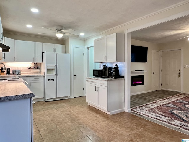 kitchen with backsplash, ornamental molding, white fridge with ice dispenser, ceiling fan, and white cabinets