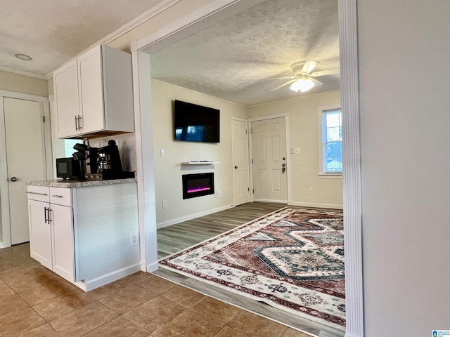 kitchen featuring ceiling fan, a textured ceiling, and white cabinets