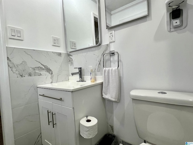 bathroom featuring vanity, tile walls, and toilet