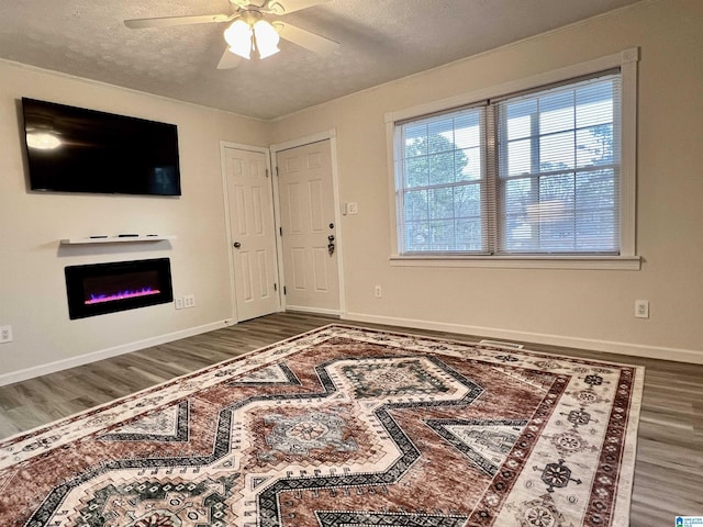 living room featuring ceiling fan, dark wood-type flooring, and a textured ceiling