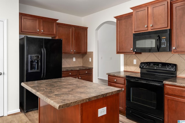 kitchen featuring a center island, decorative backsplash, light hardwood / wood-style floors, and black appliances