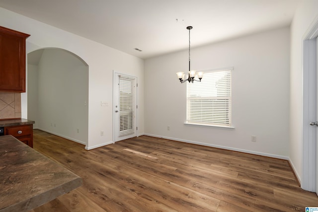 unfurnished dining area featuring dark wood-type flooring and an inviting chandelier