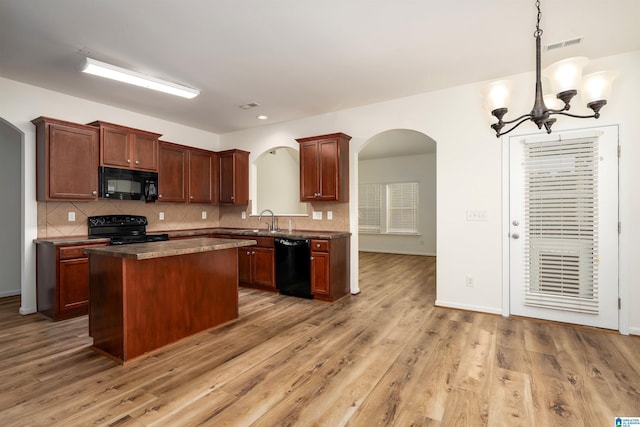 kitchen with a kitchen island, sink, backsplash, black appliances, and light wood-type flooring