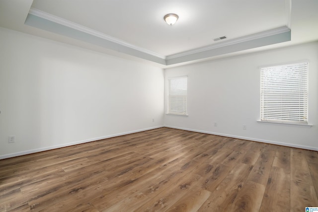 empty room with ornamental molding, hardwood / wood-style floors, and a tray ceiling