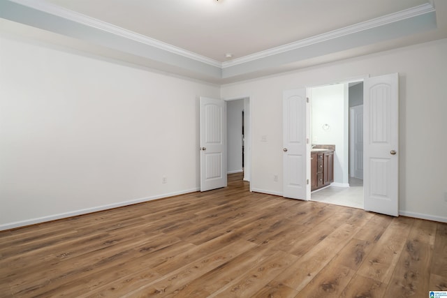 unfurnished bedroom with crown molding, wood-type flooring, and ensuite bath