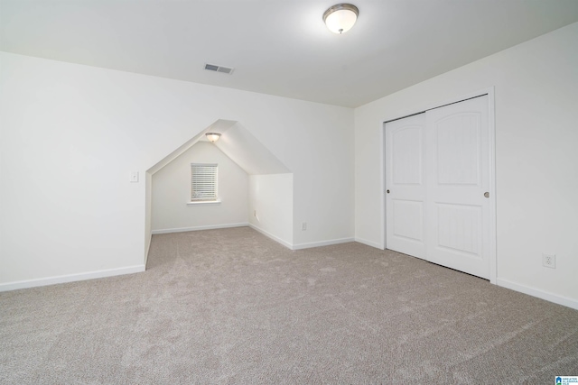 bonus room with vaulted ceiling and light carpet