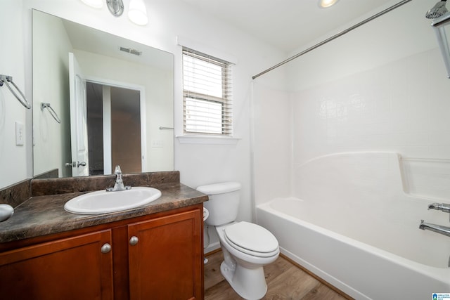 full bathroom featuring hardwood / wood-style flooring, vanity, washtub / shower combination, and toilet