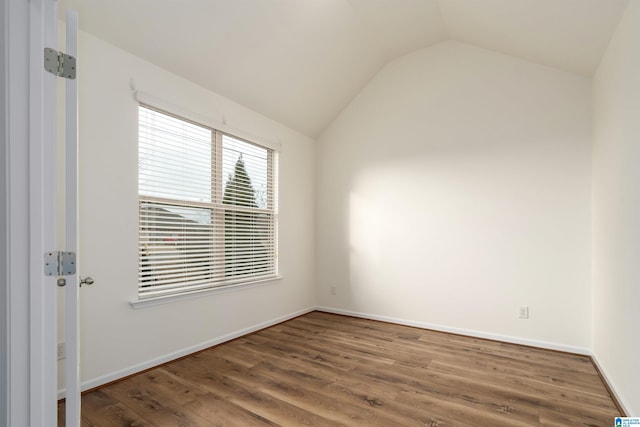 spare room featuring hardwood / wood-style flooring and lofted ceiling