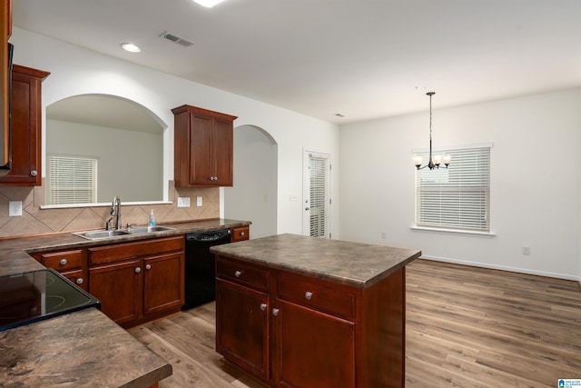 kitchen featuring sink, dishwasher, a kitchen island, decorative light fixtures, and light wood-type flooring