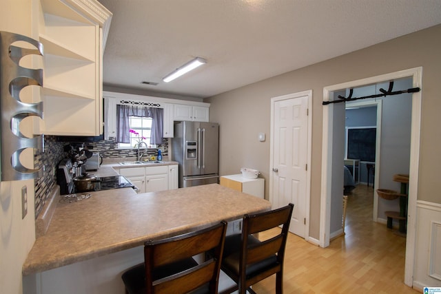 kitchen featuring sink, white cabinetry, backsplash, stove, and stainless steel fridge with ice dispenser