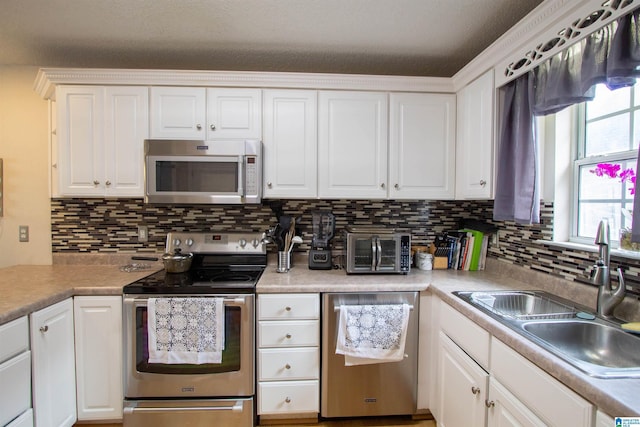 kitchen featuring stainless steel appliances, sink, white cabinets, and backsplash