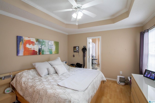 bedroom with ceiling fan, ornamental molding, a tray ceiling, and light hardwood / wood-style flooring