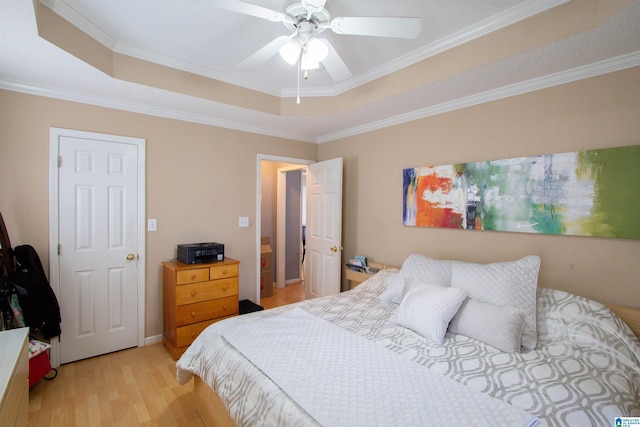 bedroom featuring crown molding, light hardwood / wood-style flooring, a raised ceiling, and ceiling fan