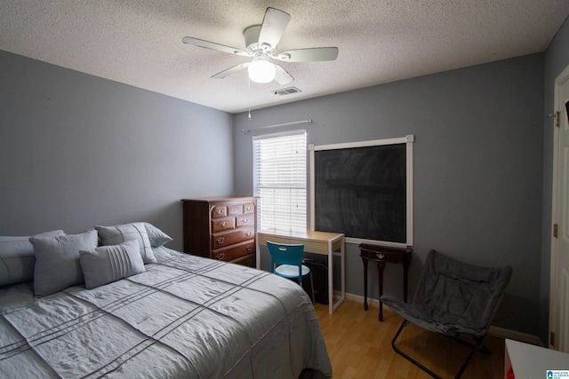 bedroom featuring ceiling fan, a textured ceiling, and light wood-type flooring