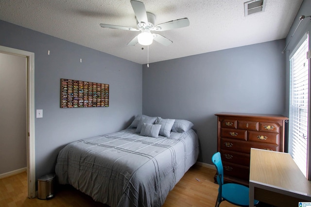 bedroom featuring hardwood / wood-style flooring, ceiling fan, and a textured ceiling