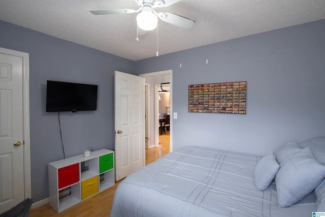 bedroom with ceiling fan, hardwood / wood-style flooring, and a textured ceiling