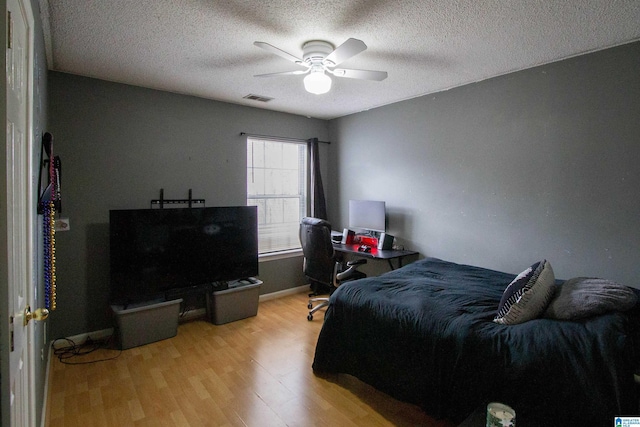 bedroom featuring ceiling fan, light hardwood / wood-style floors, and a textured ceiling