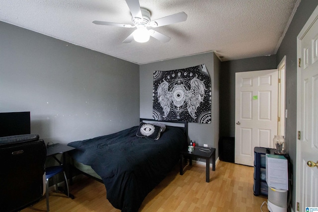 bedroom featuring ceiling fan, light hardwood / wood-style floors, and a textured ceiling