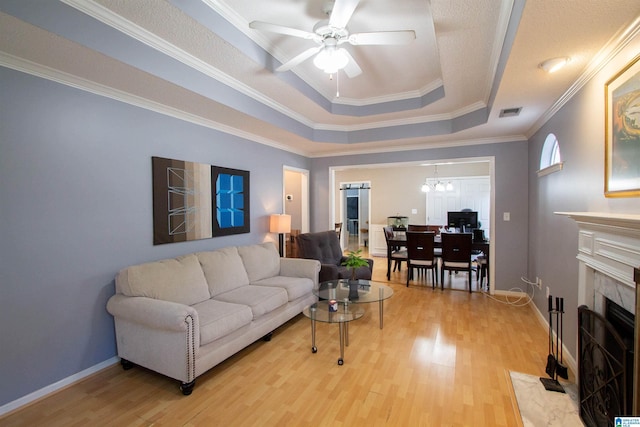 living room featuring a tray ceiling, wood-type flooring, a high end fireplace, and ceiling fan