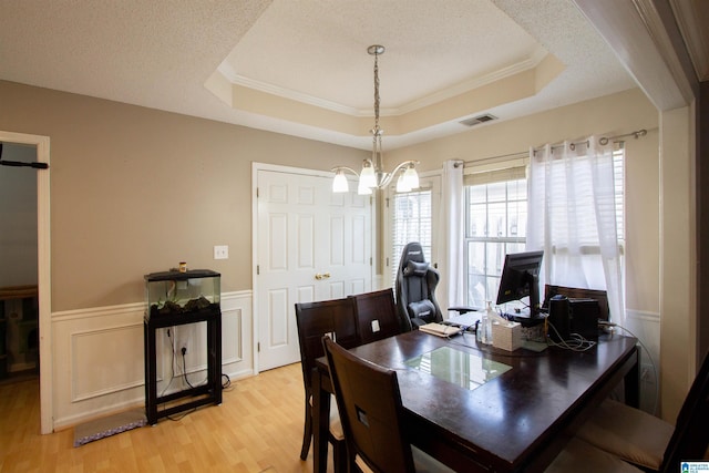 dining room featuring light hardwood / wood-style flooring, a raised ceiling, and a textured ceiling