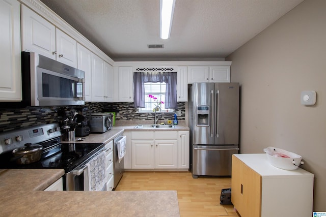 kitchen featuring sink, backsplash, stainless steel appliances, and white cabinets